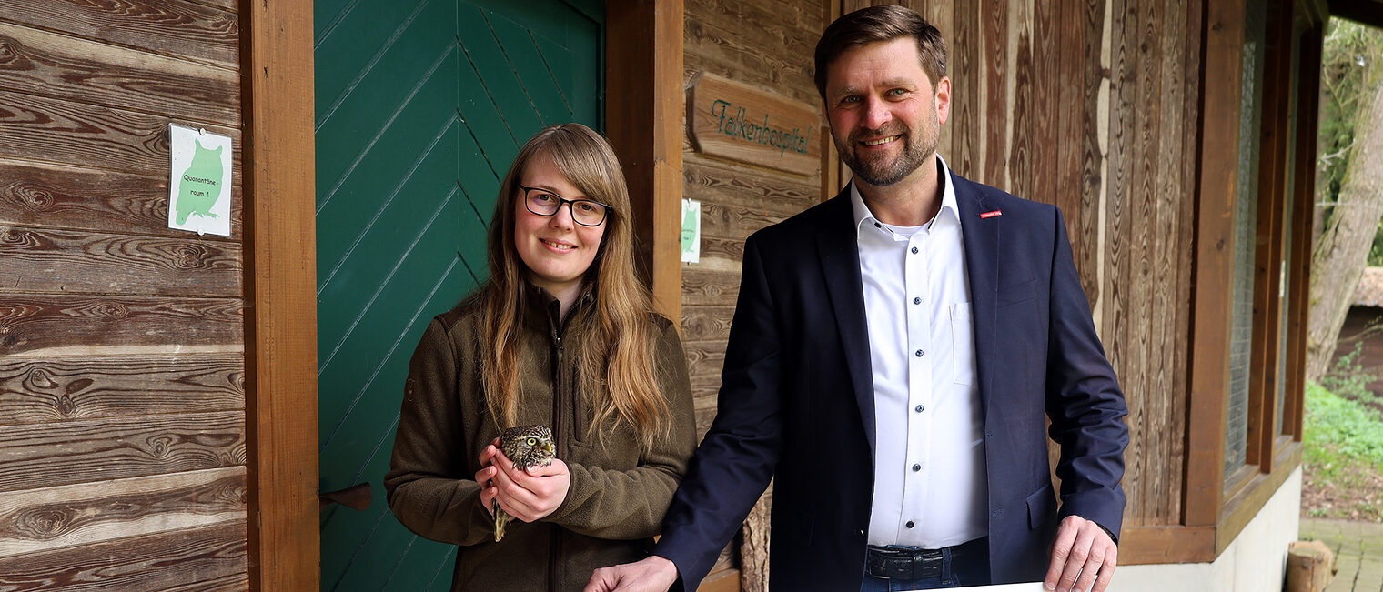 Hendrik Schmitt (HwK Südwestfalen) überreicht einen Scheck an Anna Reichel (Vogelpflegestation). Reichel hält einen Waldkauz.
