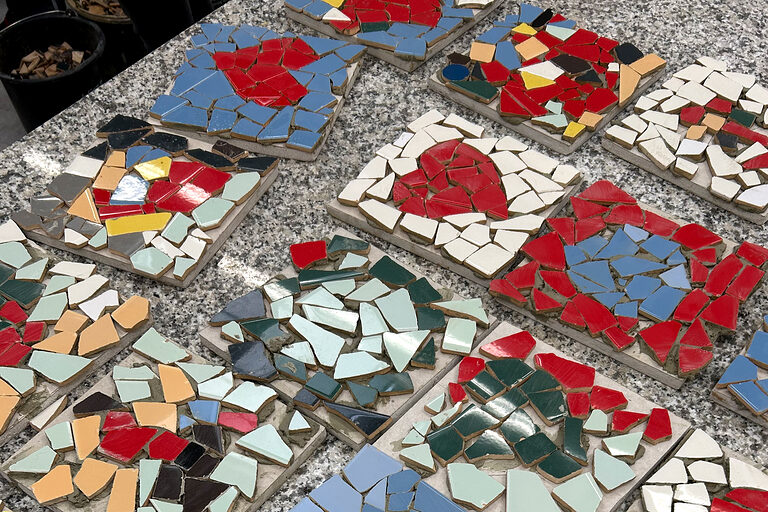 Verschiedene bunte Mosaikbilder liegen auf einem Tisch.