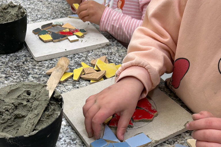 Nahaufnahme, wie zwei Kinder an Mosaikbildern arbeiten.