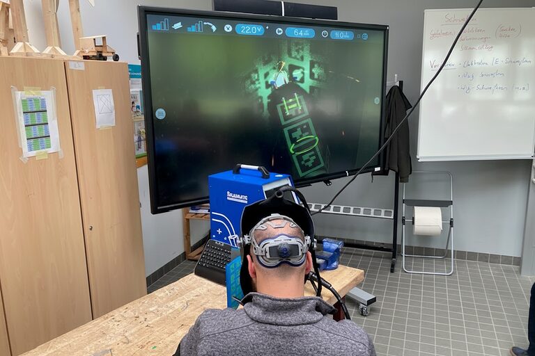 Ein Mann arbeitet mit einer Virtual-Reality-Brille an einem Schweißsimulator.
