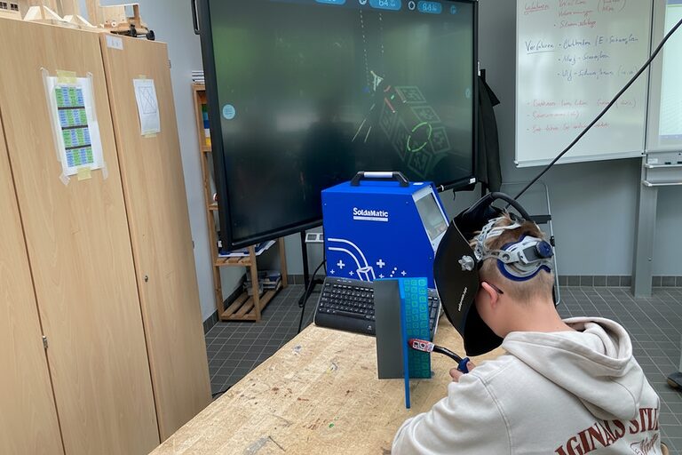 Ein Schüler arbeitet mit einer Virtual-Reality-Brille an einem Schweißsimulator.