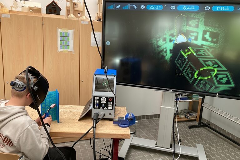 Ein Schüler arbeitet mit einer Virtual-Reality-Brille an einem Schweißsimulator.