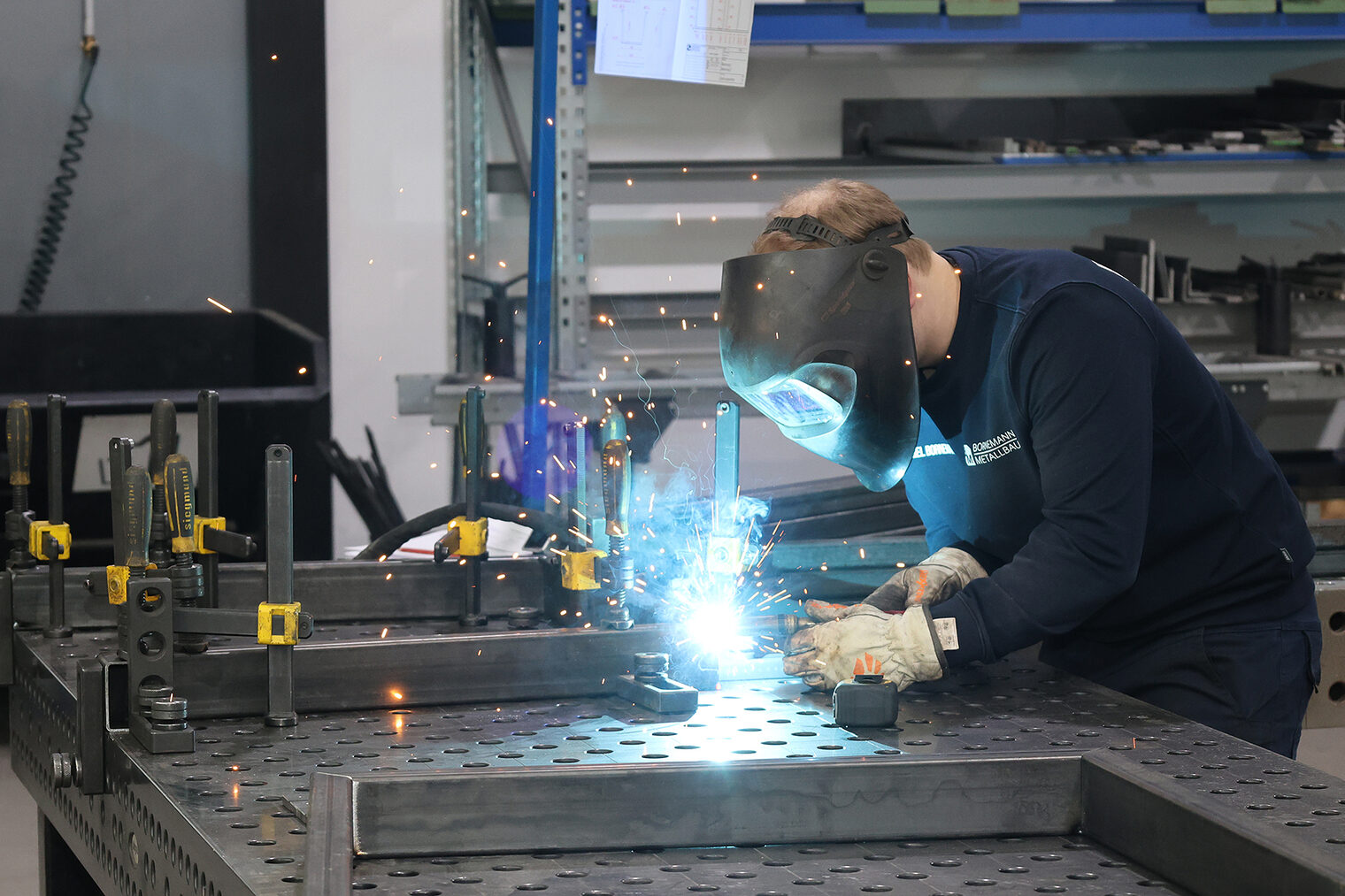 Ein Metallbauer beim Schweißen von Metallteilen in einer Werkstatt.