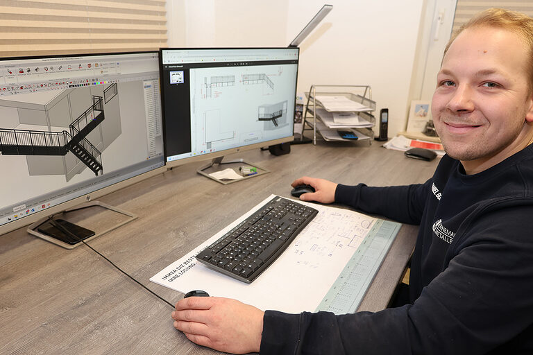 Metallbauermeister Daniel Bornemann sitzt am Schreibtisch und plant ein Geländer.