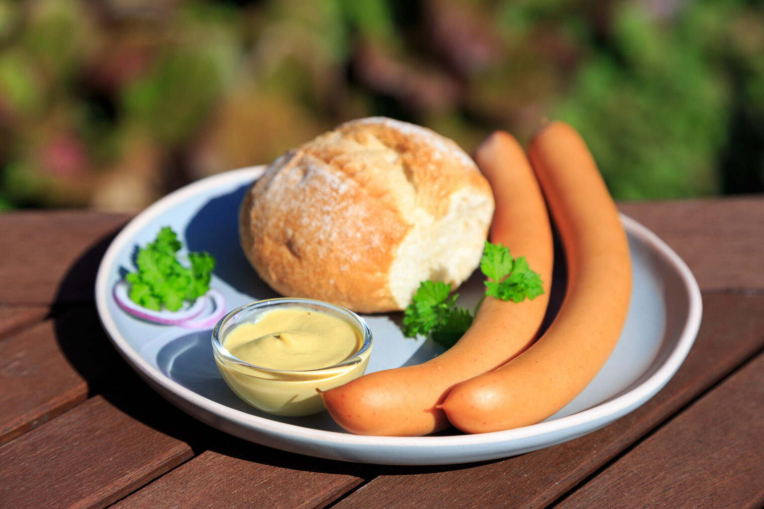 Ein Brötchen mit Bockwürstchen auf einem Teller.
