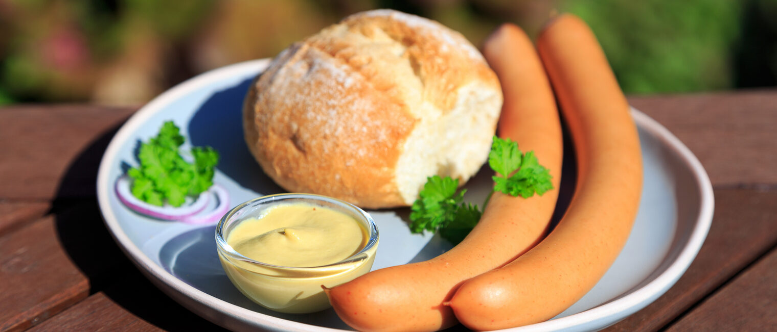 Ein Brötchen mit Bockwürstchen auf einem Teller.