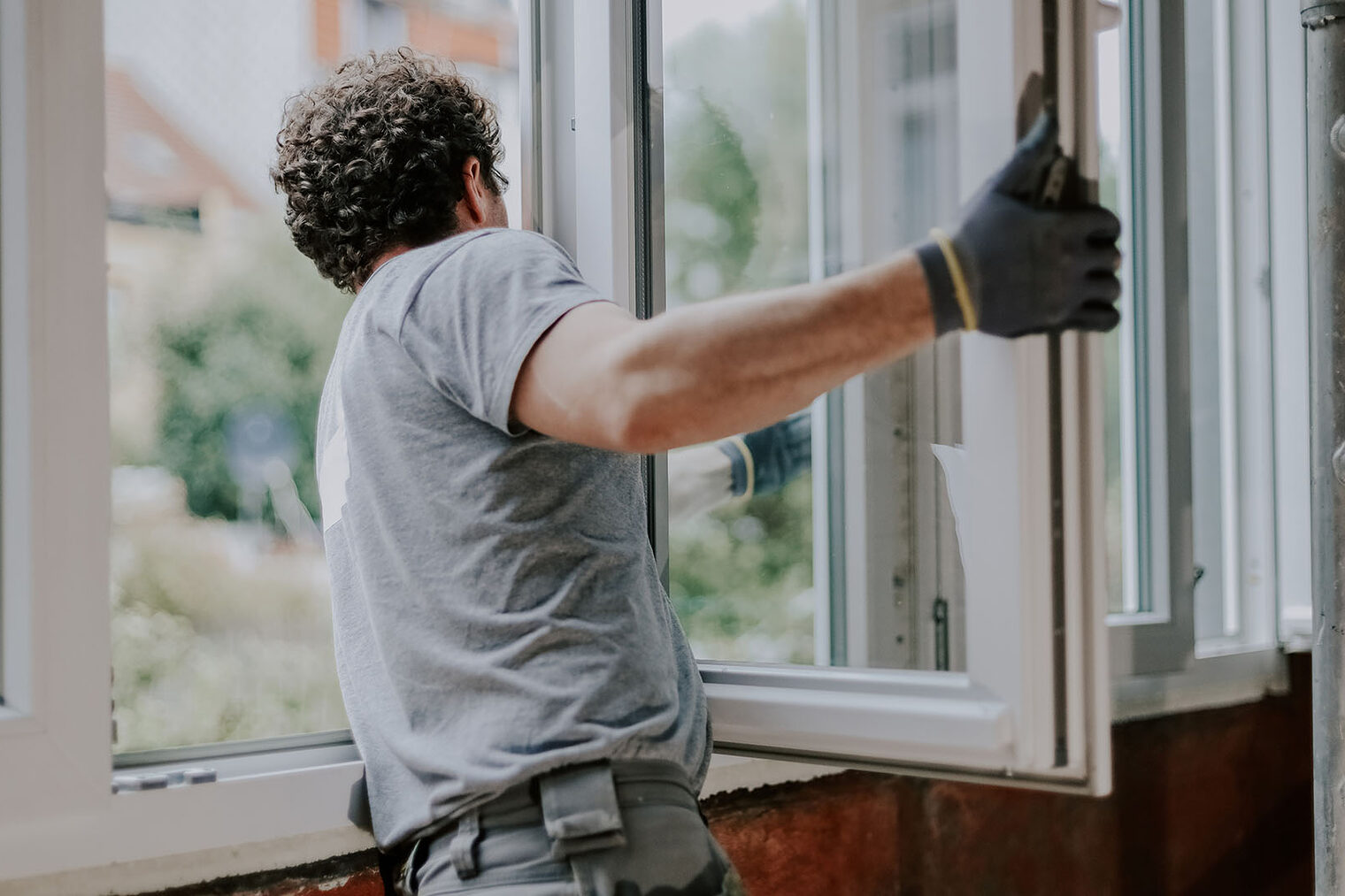 Ein Mann baut ein Fenster ein.