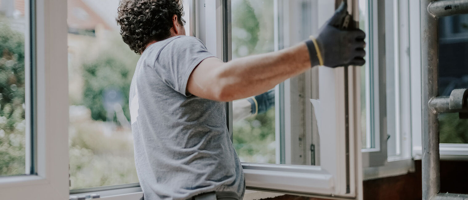 Ein Mann baut ein Fenster ein.