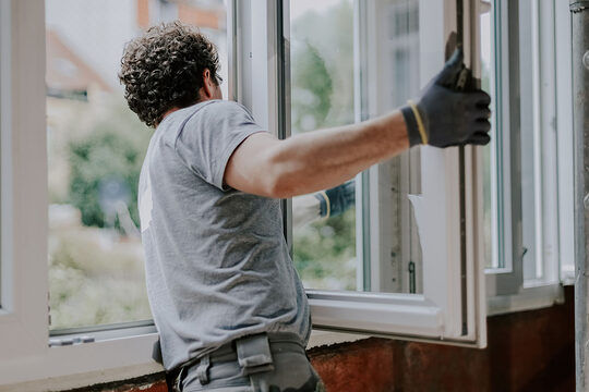 Ein Mann baut ein Fenster ein.
