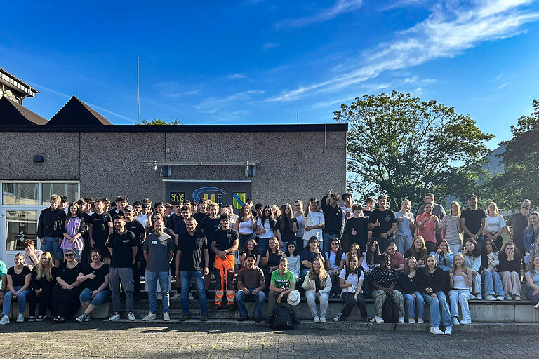 Grupopenfoto mit Schülern und Handwerkern vor einem Schulgebäude