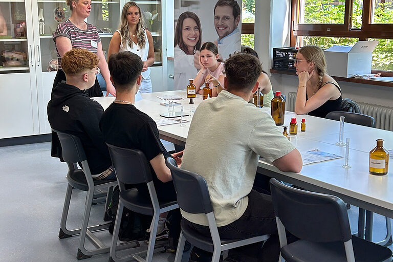 Zwei Vertreter der Gesundheitsfachschule für PTA halten einen Vortrag vor Schülern in einem Klassenraum.