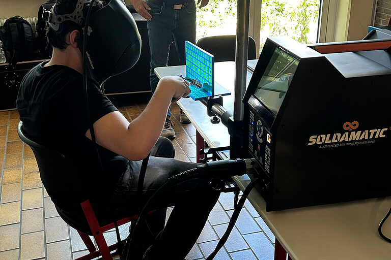 Ein Schüler zieht am Virtual-Reality-Schweißsimulator eine virtuelle Schweißnaht.