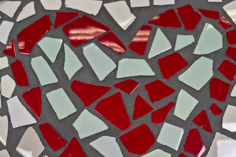 Ein rotes Mosaikherz mit heller Umrandung.