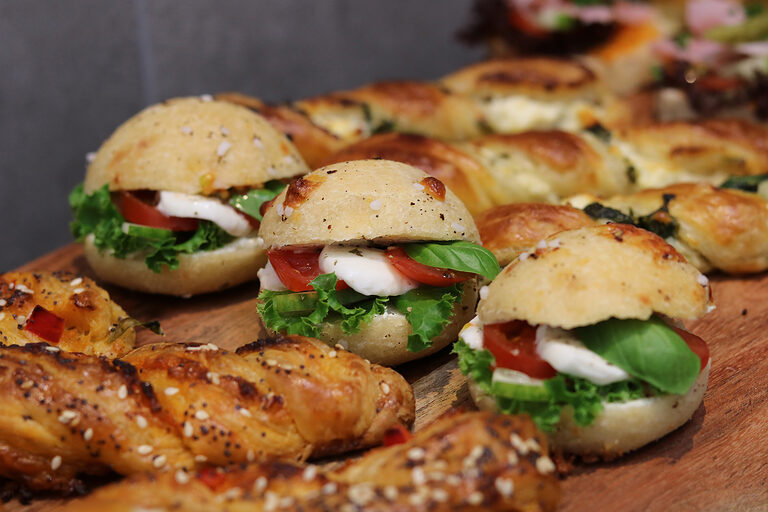Nahaufnahme von frisch belegten Brötchen mit Tomate, Mozzarella und Salat.