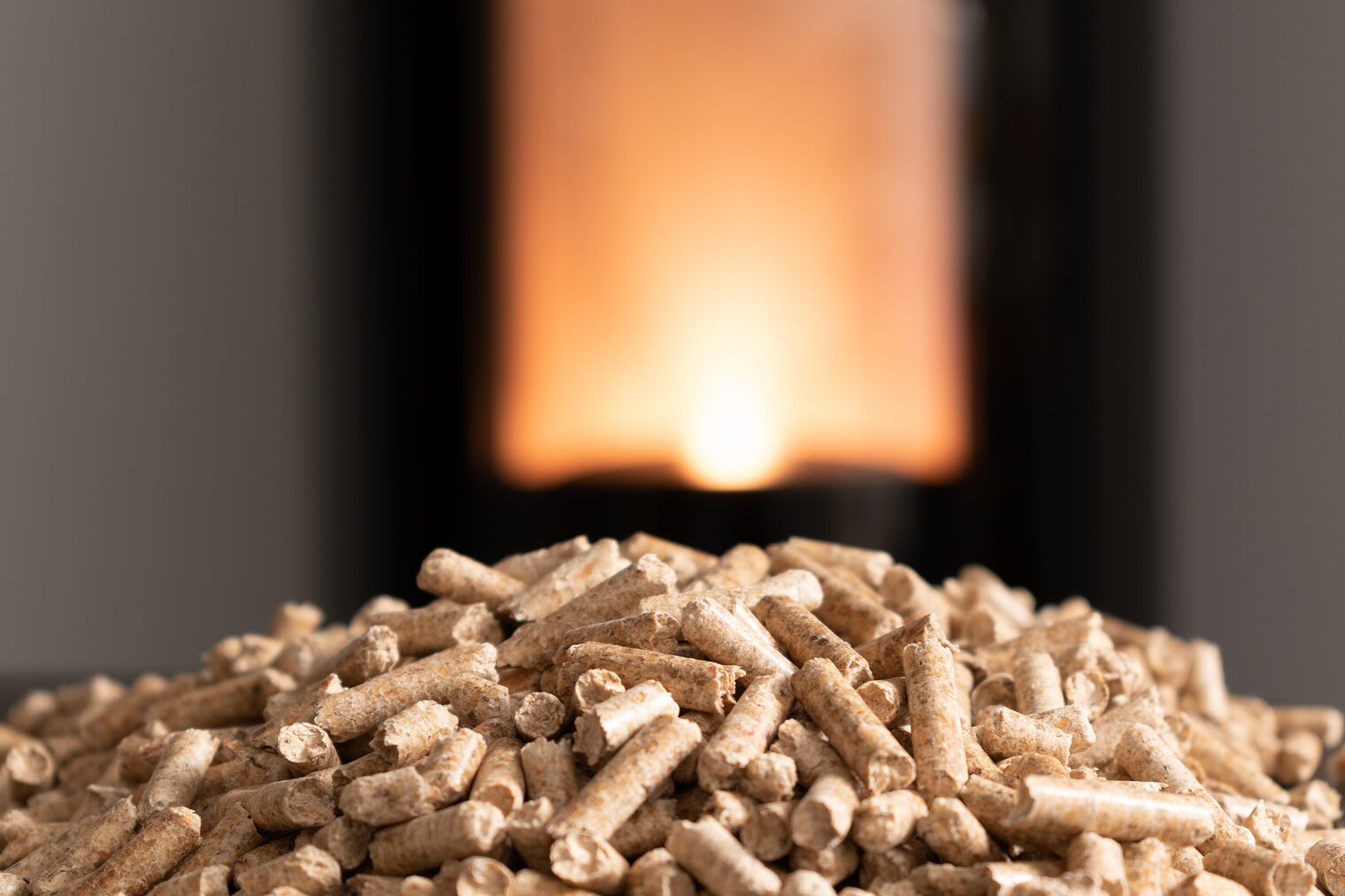 Ein Haufen Holzpellets, im Hintergrund ein Ofen.