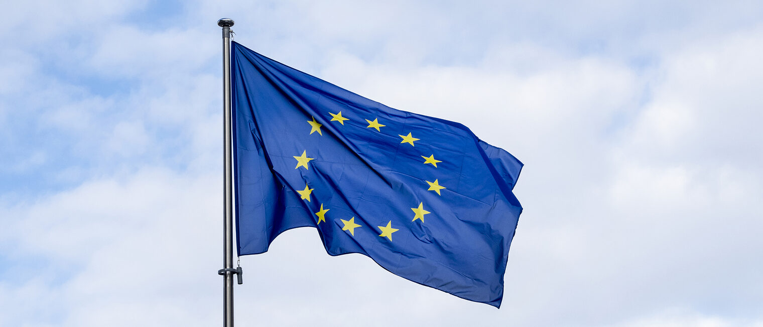 Aufnahme einer EU-Flagge vor einem teilweise bewölktem Himmel.
