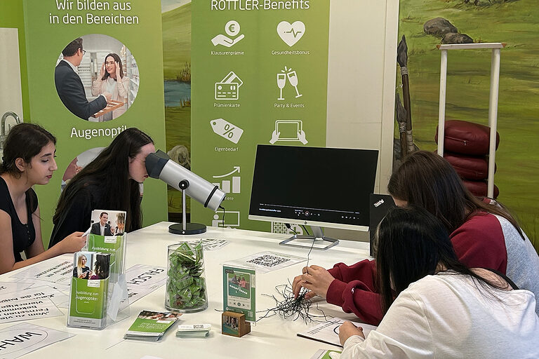Schülerinnen führen einen Sehtest am Stand von Brillen Rottler durch