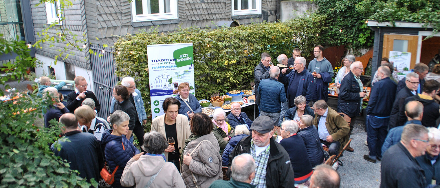 Viele Menschen im Museumsgarten Haus Hövener unterhalten sich und essen und trinken etwas.