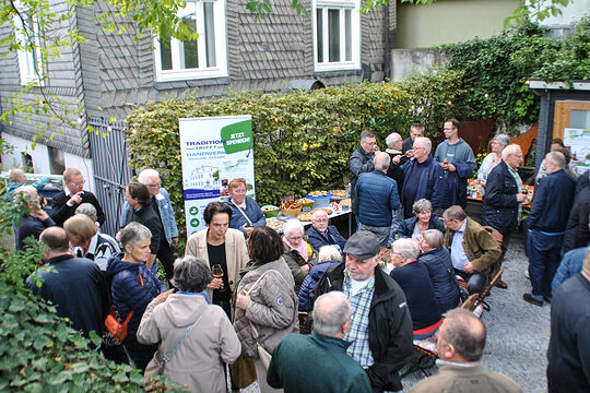 Viele Menschen im Museumsgarten Haus Hövener unterhalten sich und essen und trinken etwas.