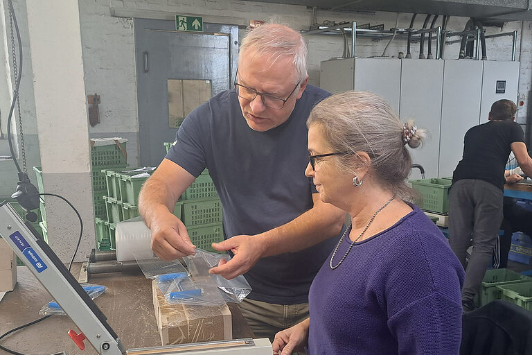 Ein Mann und eine Frau arbeiten in einem metallverarbeitenden Betrieb zusammen.