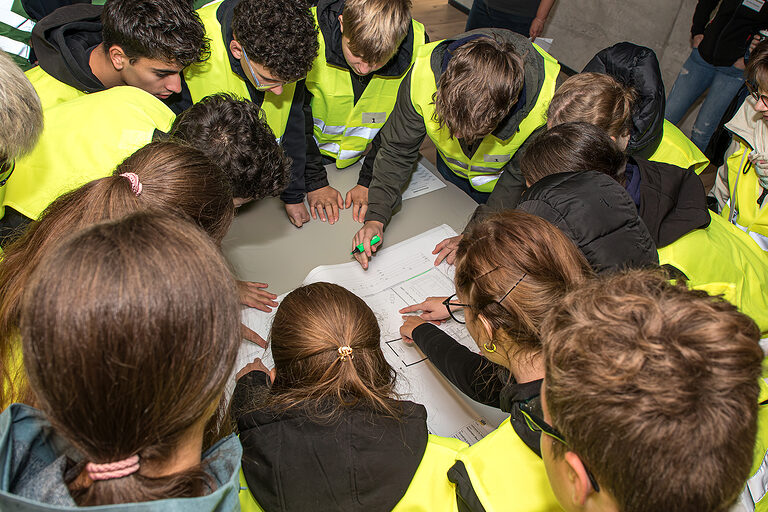 Eine Gruppe Schülerinnen und Schüler bespricht einen Bauplan bei der Heckmann Bau Handwerkschallenge