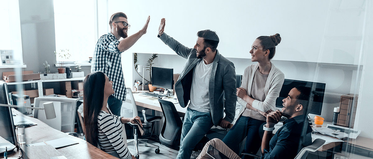 Two cheerful young business people giving high-five while their colleagues looking at them and smiling Schlagwort(e): Men, Women, People, Corporate Business, Modern, Success, Expertise, High-Five, Celebration, Group Of People, Office, Business, Creative Occupation, Multi-Ethnic Group, New Business, Solution, Working, Meeting, Brainstorming, Design Studio, Business Finance And Industry, Cooperation, Technology, Professional Occupation, Togetherness, Unity, Discussion, Smart Casual, Business Casual, Teamwork, Team, Ideas, Planning, Strategy, Coworker, Standing, Sitting, Leaning, Indoors, Talking, Smiling, Happiness, Gesturing, Beard, Transparent, Glass-Material
