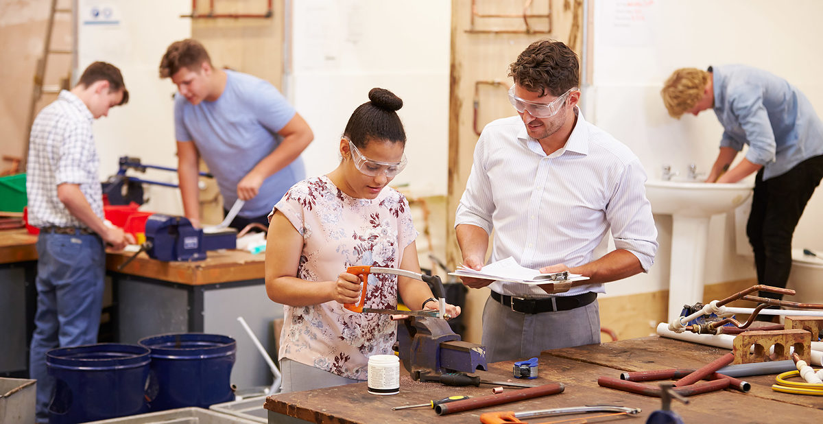 Teacher Helping College Students Studying Plumbing Wearing Protective Goggles Schlagwort(e): 16-17 Years, 18-19 Years, 30s, African Descent, African Ethnicity, Assistance, Caucasian, Cheerful, Classroom, Craft, Education, Female, Four People, Horizontal, Instructor, Learning, Little Boys, Male, Men, Occupation, People, Pipe, Plumber, Protective Eyewear, Saw, Sawing, Skill, Smiling, Student, Studying, Support, Teacher, Teenage Girls, Teenager, Togetherness, Trainee, Training, University, Water Pipe, Work Tool, Working, Workshop