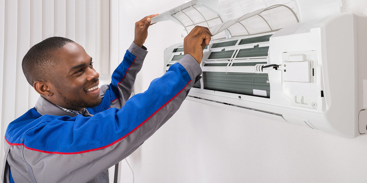Happy Male Technician Checking Air Conditioner At Home